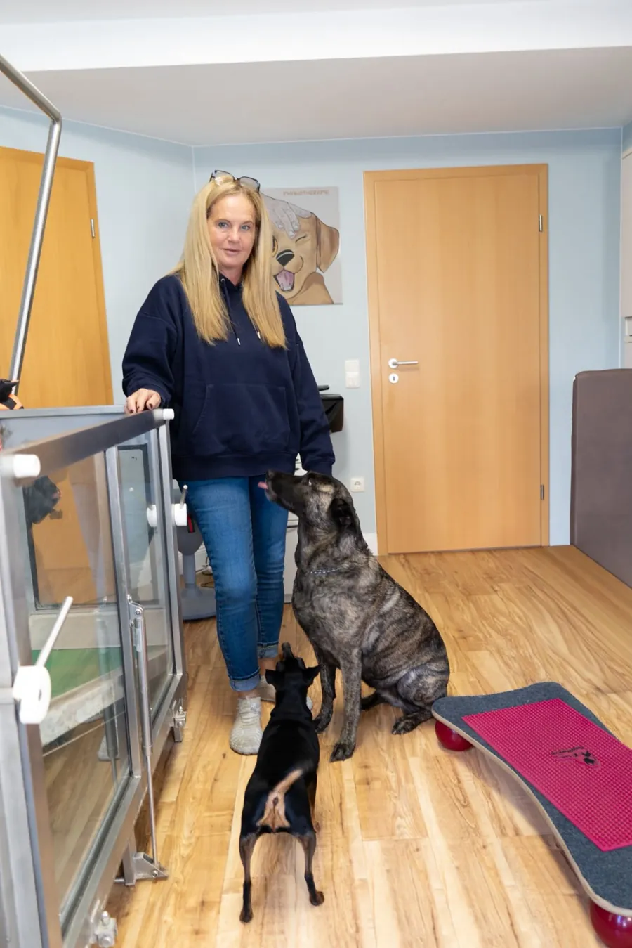 Alexandra Ulrich steht mit zwei Hunden am Unterwasserlaufband ihrer Praxis