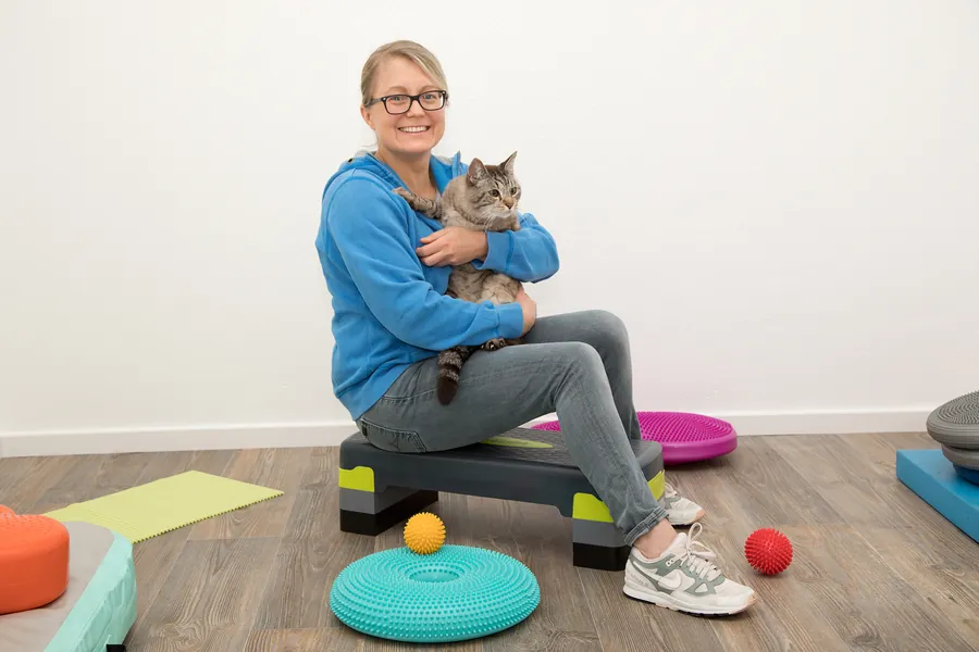 Vicky Schneider sitzt mit einer getigerten Katze im Arm in der Praxis